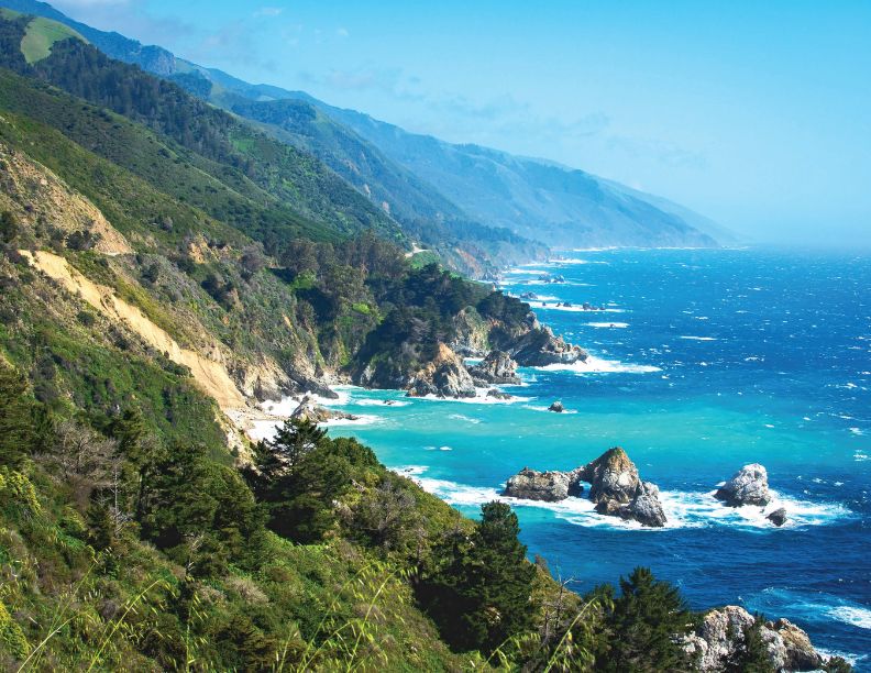 January 2027, Tree covered mountains meeting a beach with bright blue water