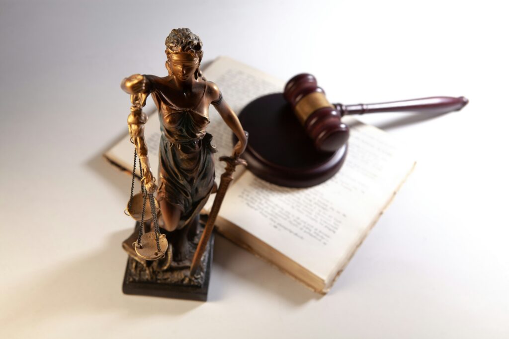 A desktop statue of Lady Justice, open legal book, and gavel