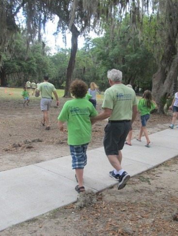 Image of Lou Fioritto (Founder & Co-Owner of Braille Works) walking with his grandson during a company picnic.